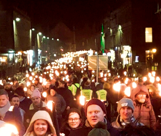 Fiume di torce durante la Torchlight Procession di Edimburgo verso la Città Vecchia.
